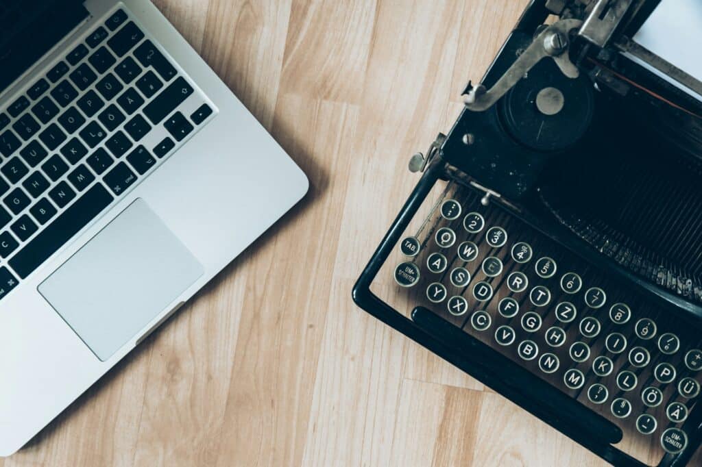 A laptop and a typewriter on a wooden desk, reflecting the differences for sage intacct versus sage 100