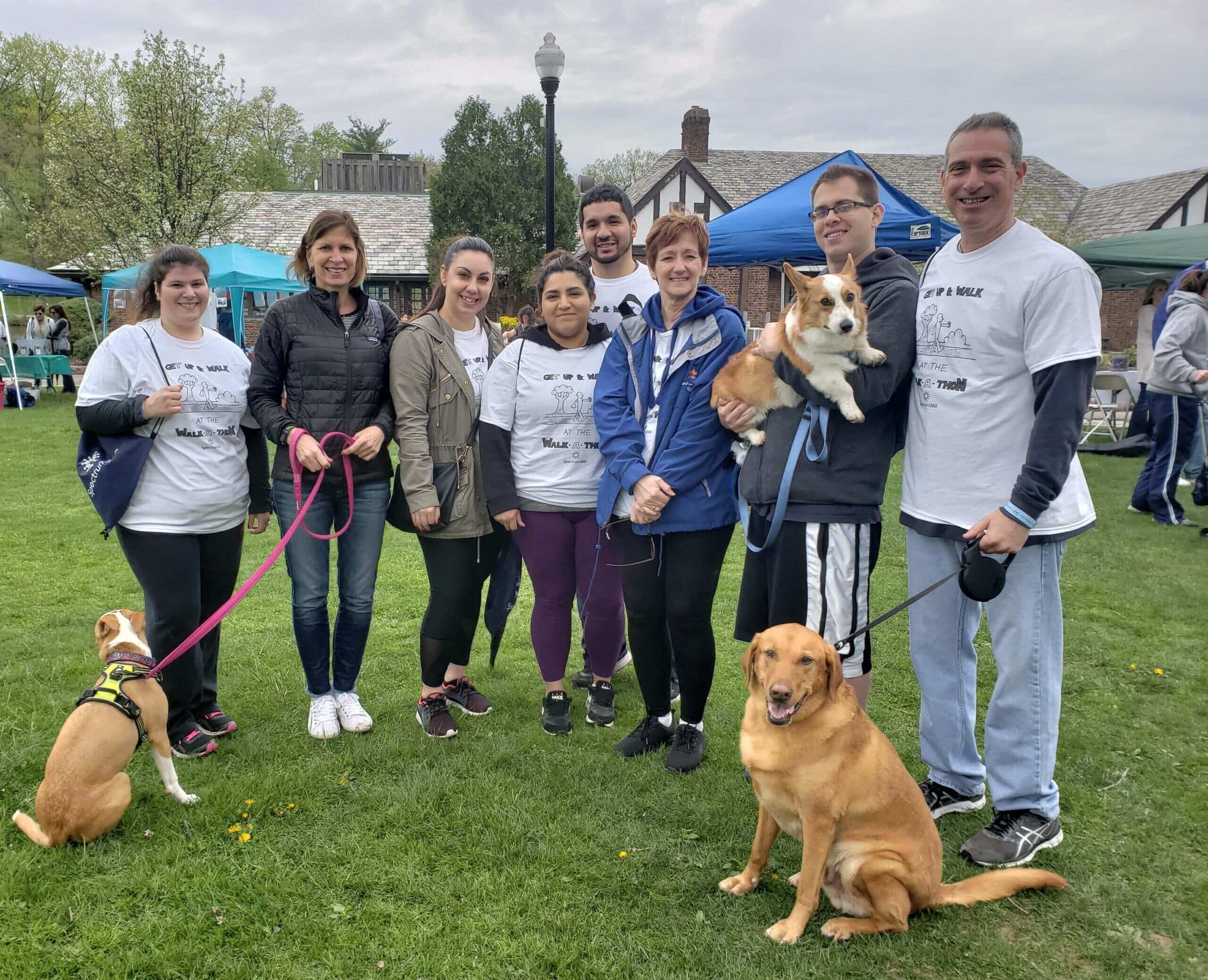 A group of people posing for a photo with their dogs.