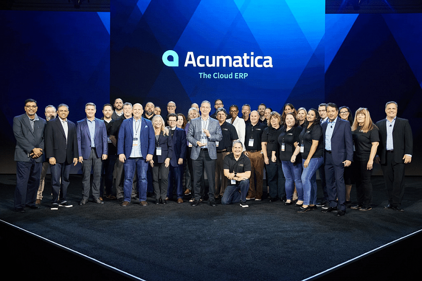 A group of people standing on a stage with the word Acumatica.
