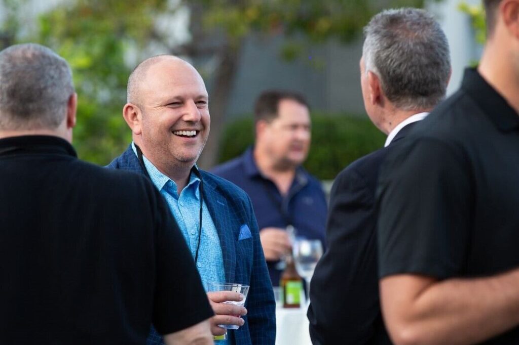 A group of men laughing at an outdoor event.