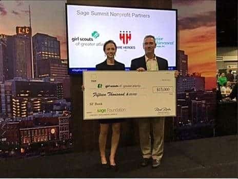 Two people standing in front of a large check.