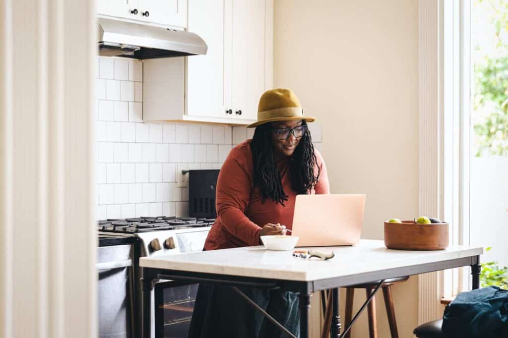 A woman working on her laptop in a kitchen.