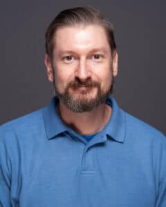 A man with a beard and a blue shirt.