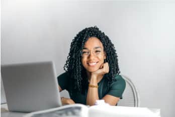 A young woman sitting at a desk with a laptop.