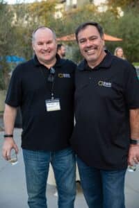 Two men in black shirts standing next to each other.