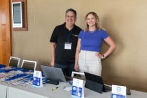 Two people standing in front of a table with laptops.