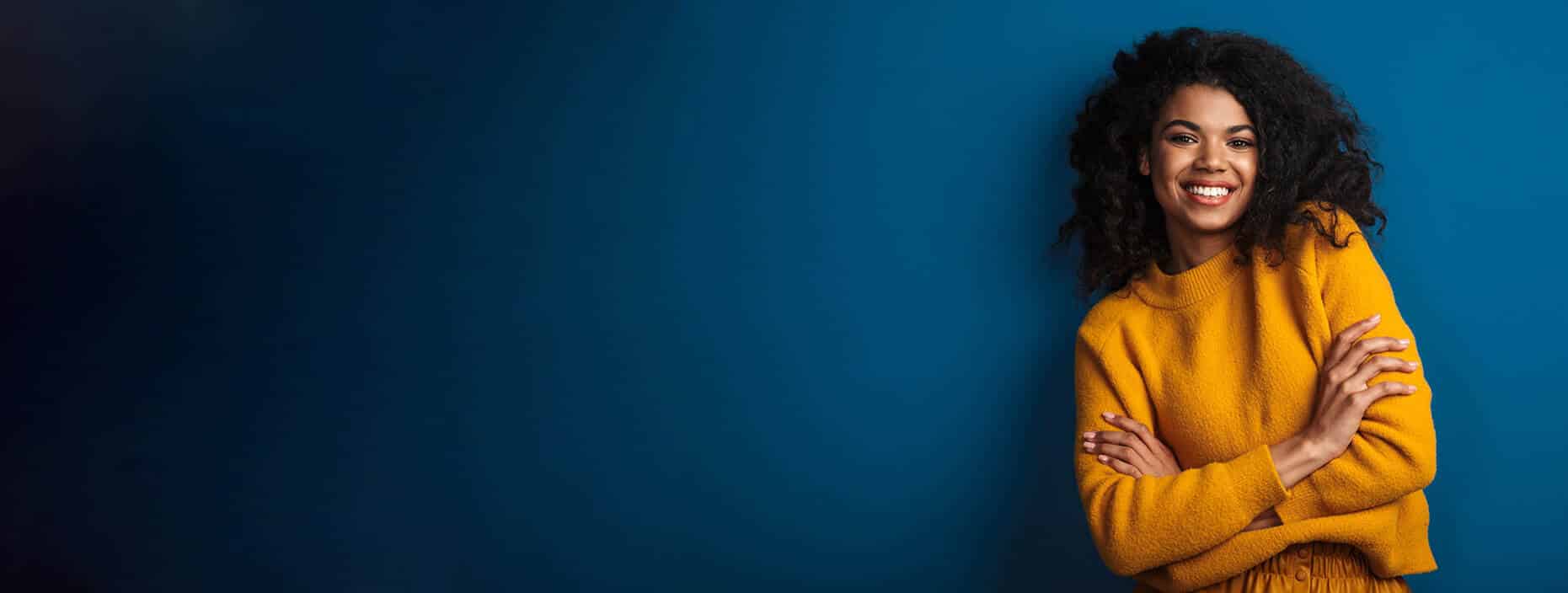 Young woman with curly hair posing against a blue background.