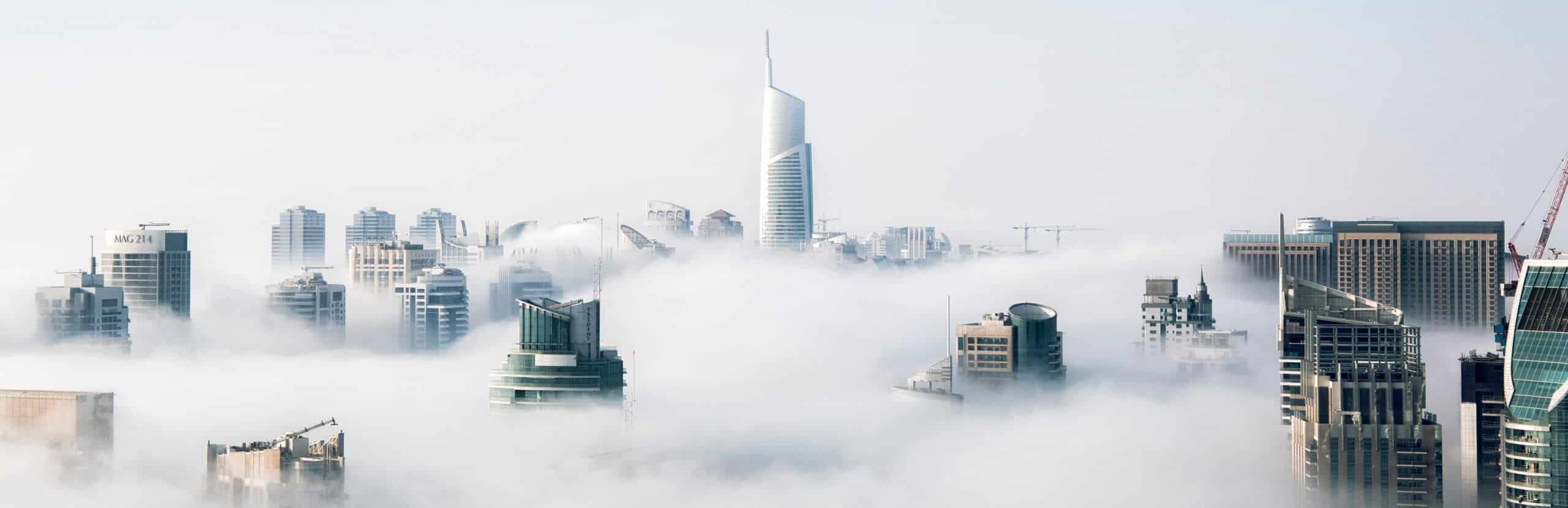A city covered in clouds with tall buildings in the background.