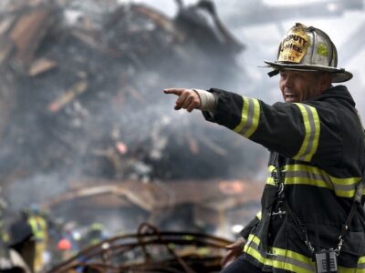 A firefighter pointing at a pile of rubble.