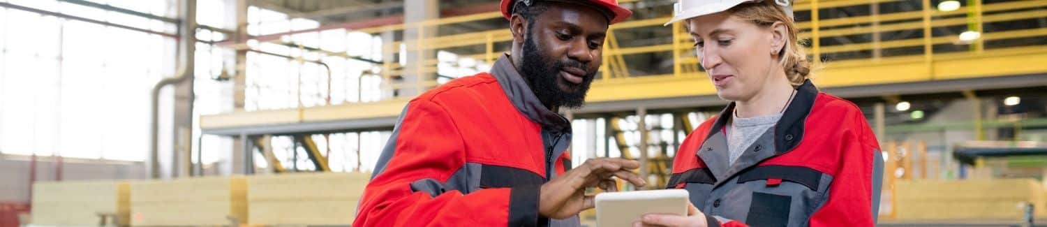 A group of people in a factory looking at a tablet.