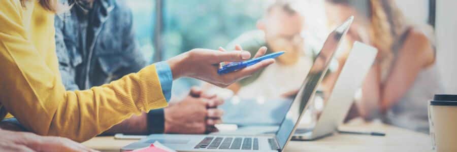 A group of people sitting around a table with laptops.