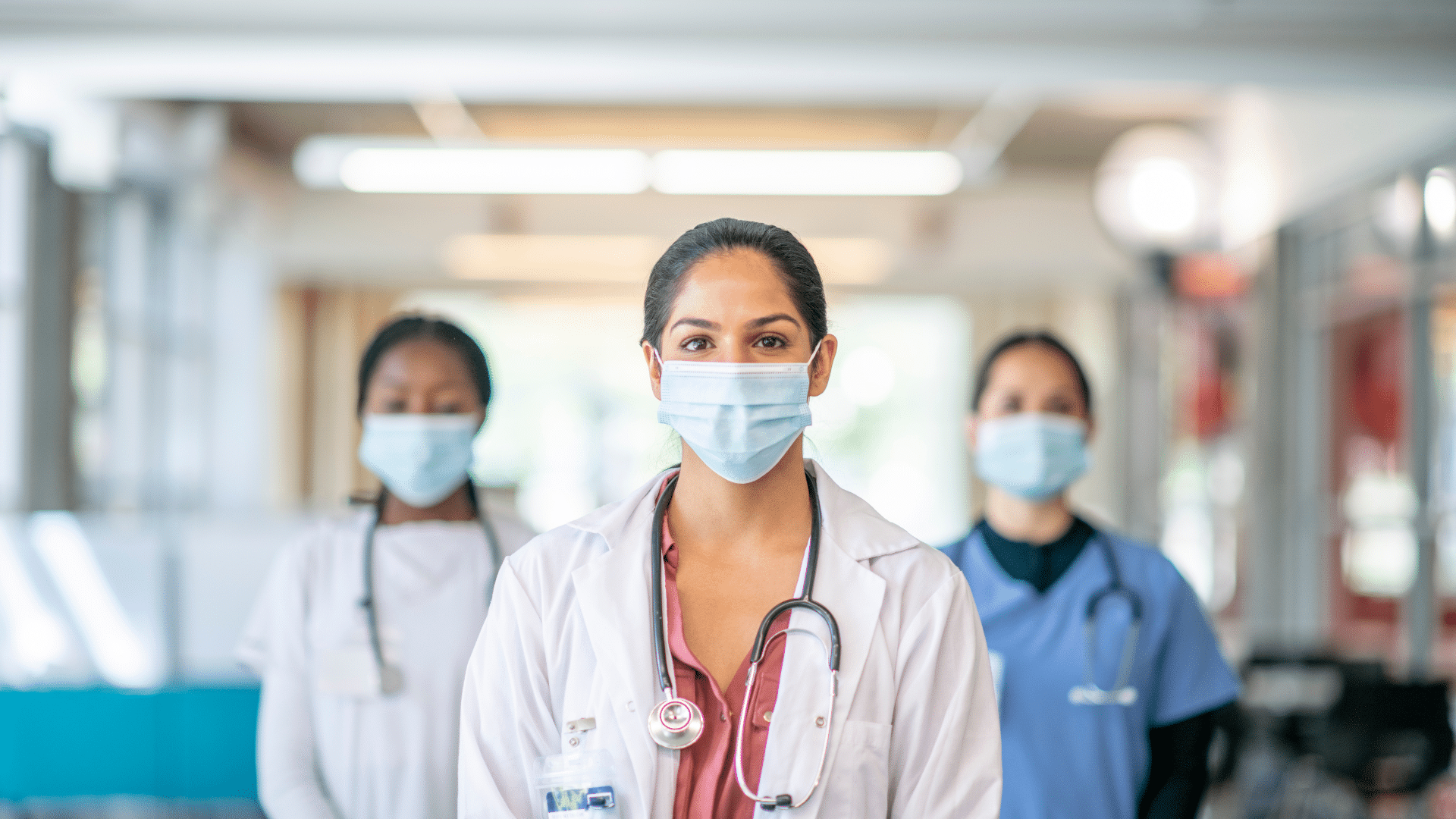 A group of nurses wearing surgical masks in a hospital hallway.