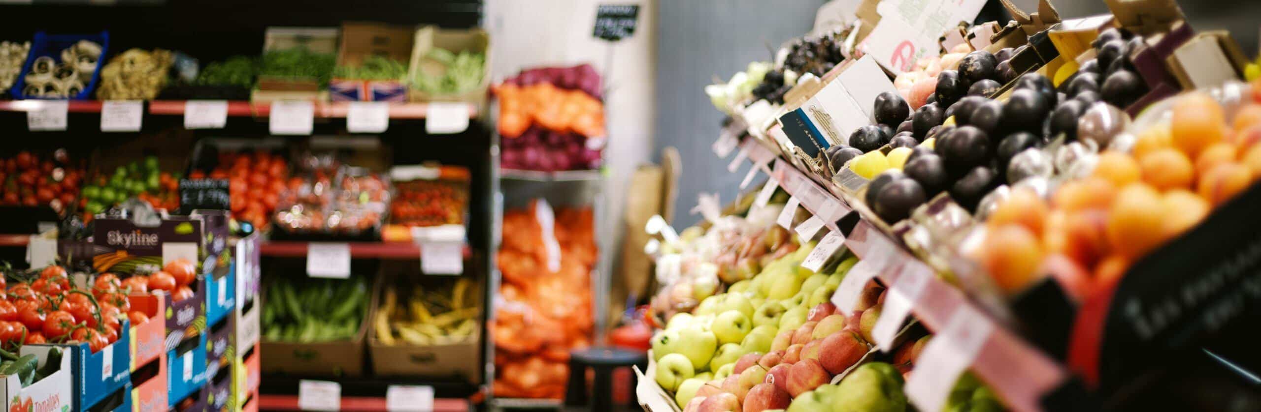 A row of fruits and vegetables in a grocery store.