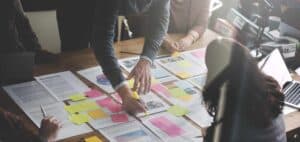 A group of people sitting around a table with sticky notes.