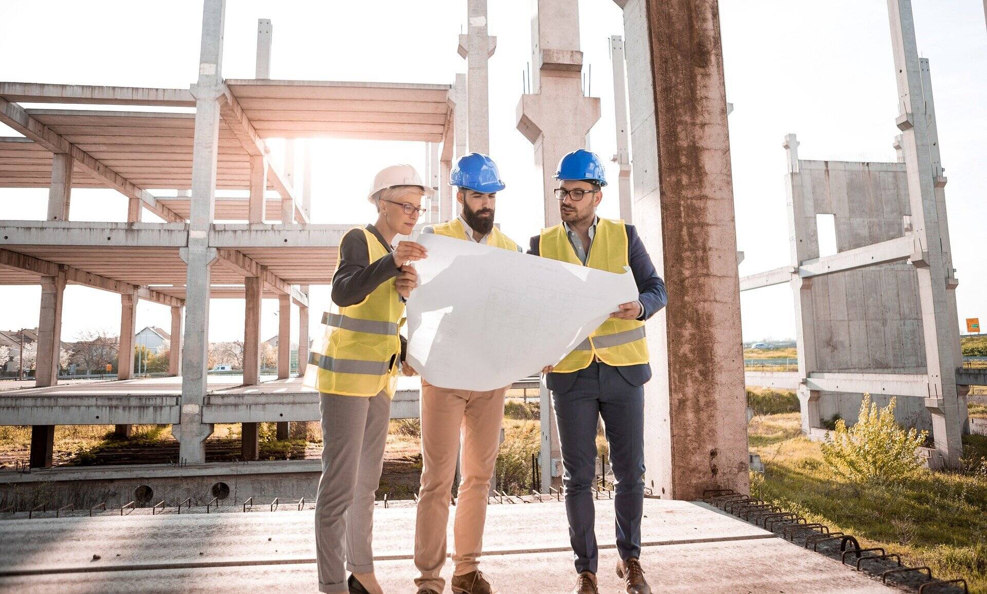 Three construction workers looking at a blueprint at a construction site.