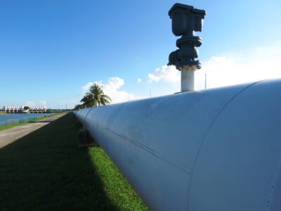 A large white pipe next to a grassy area.