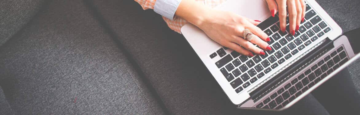 A woman is sitting on a couch with a laptop.