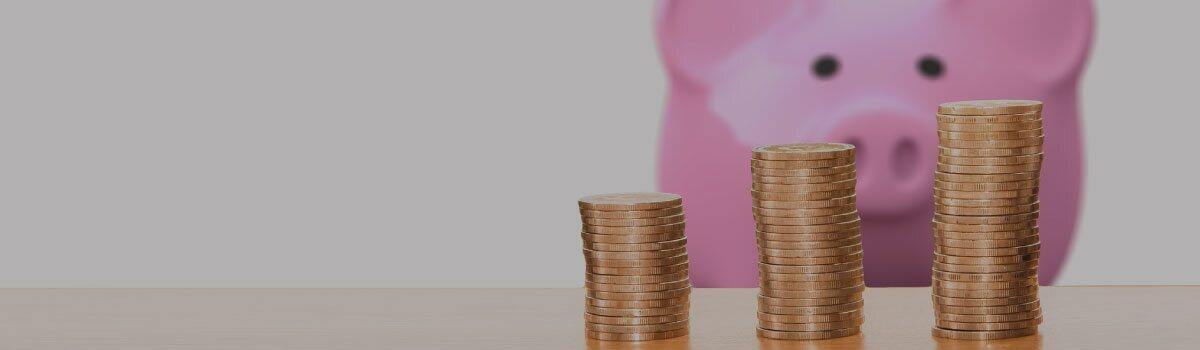 A stack of coins next to a piggy bank.