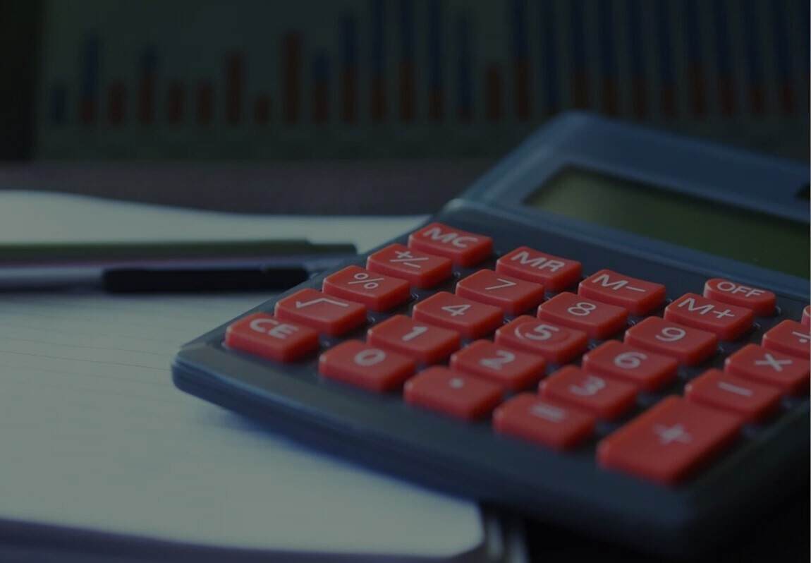 A red calculator sits on top of a notebook.