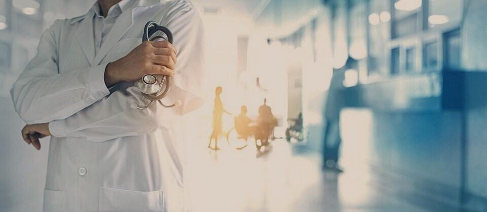 A doctor with a stethoscope is standing in a hallway.