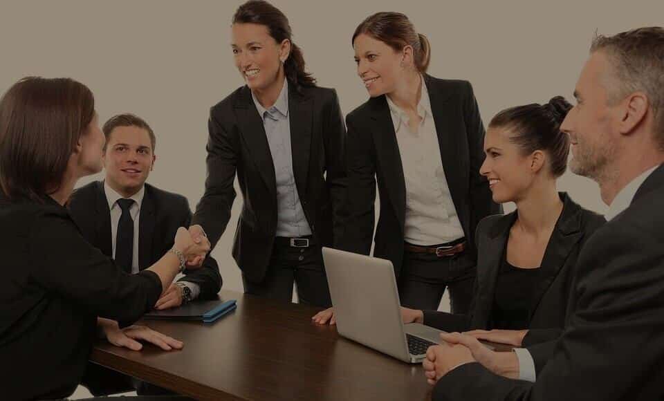 A group of business people shaking hands around a table.