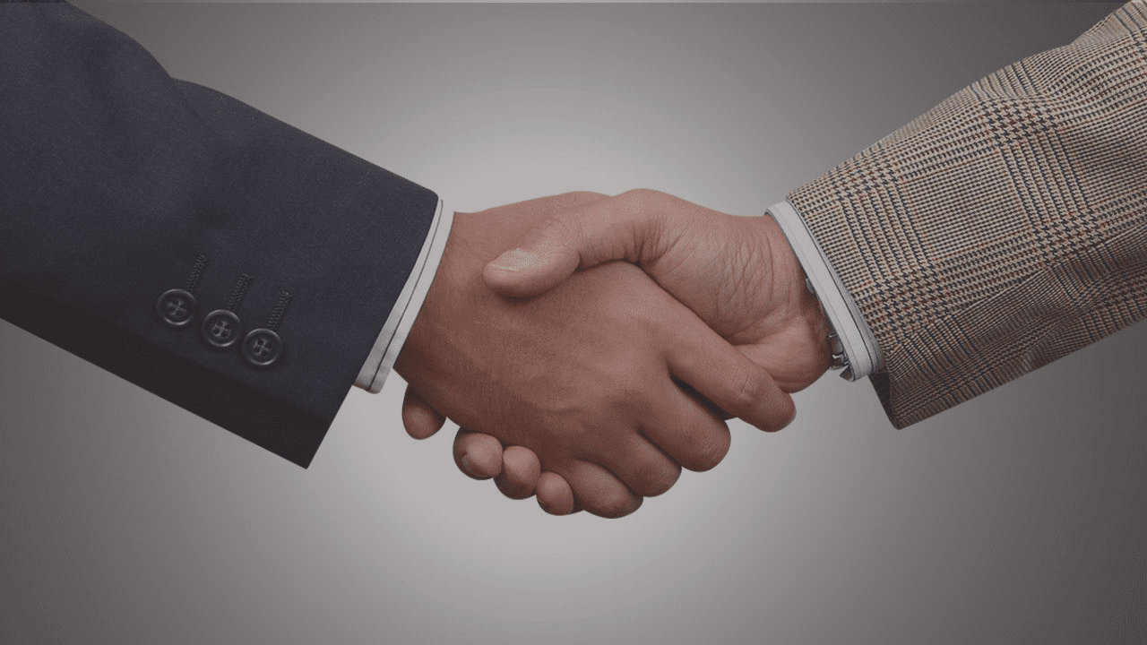 Two businessmen shaking hands against a gray background.