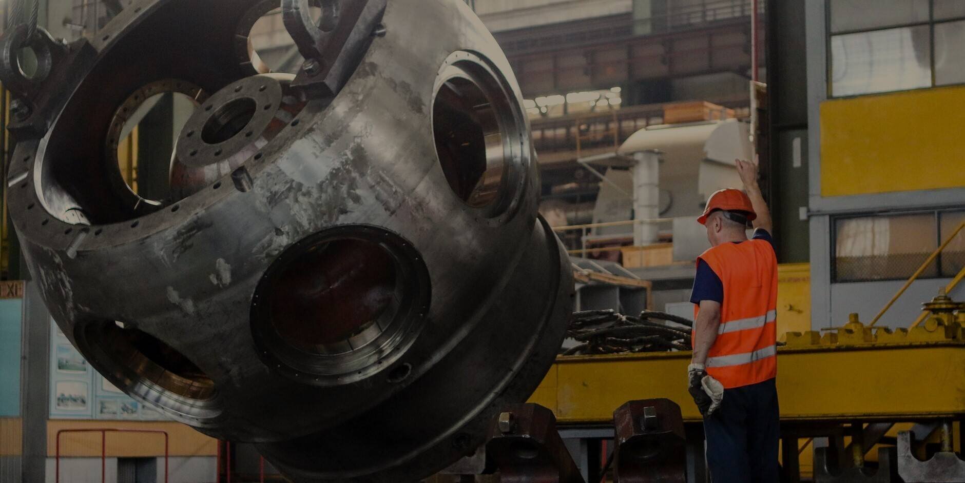 A worker inspecting a large metal wheel in a factory.