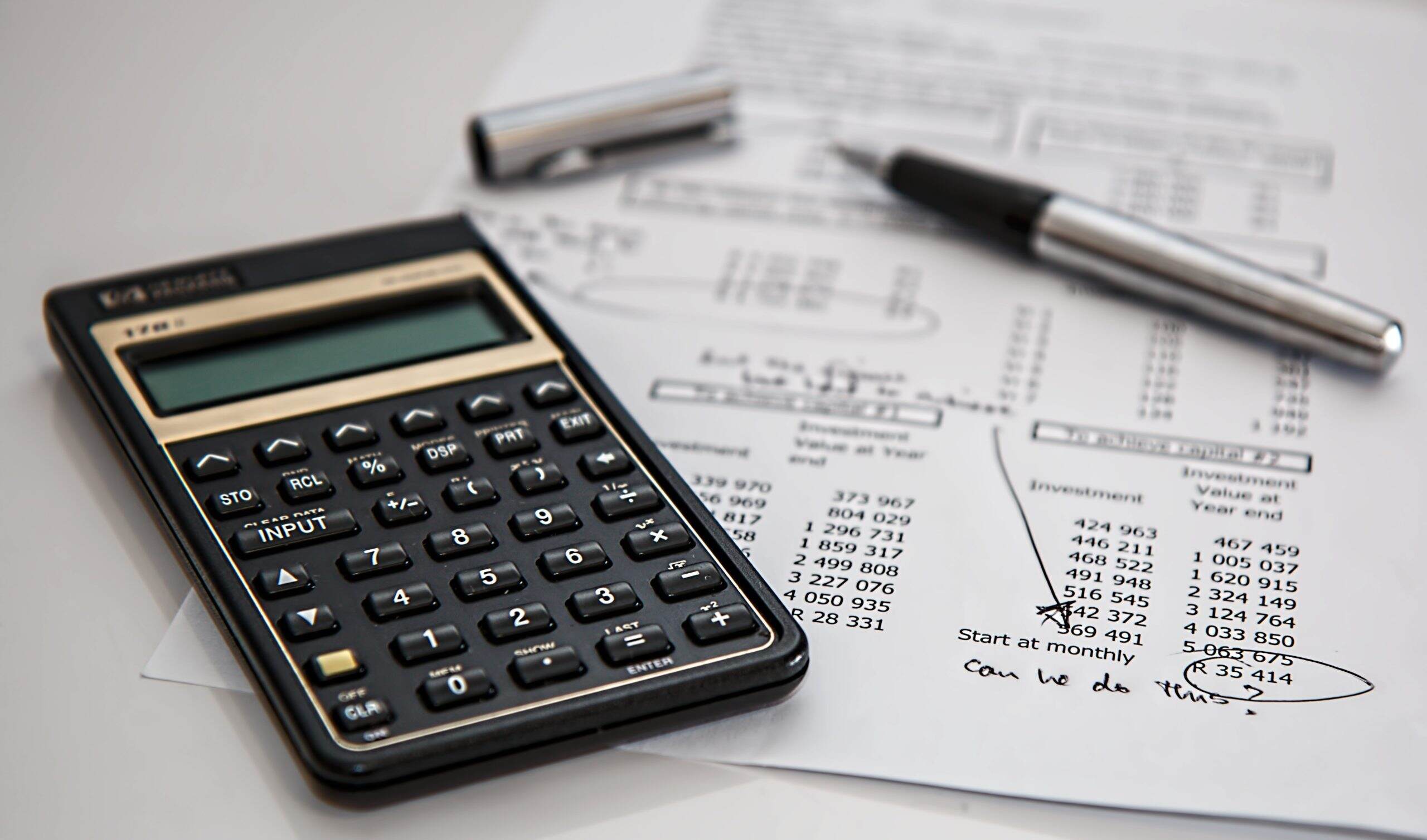 A calculator, pen and paper on top of a sheet of paper.