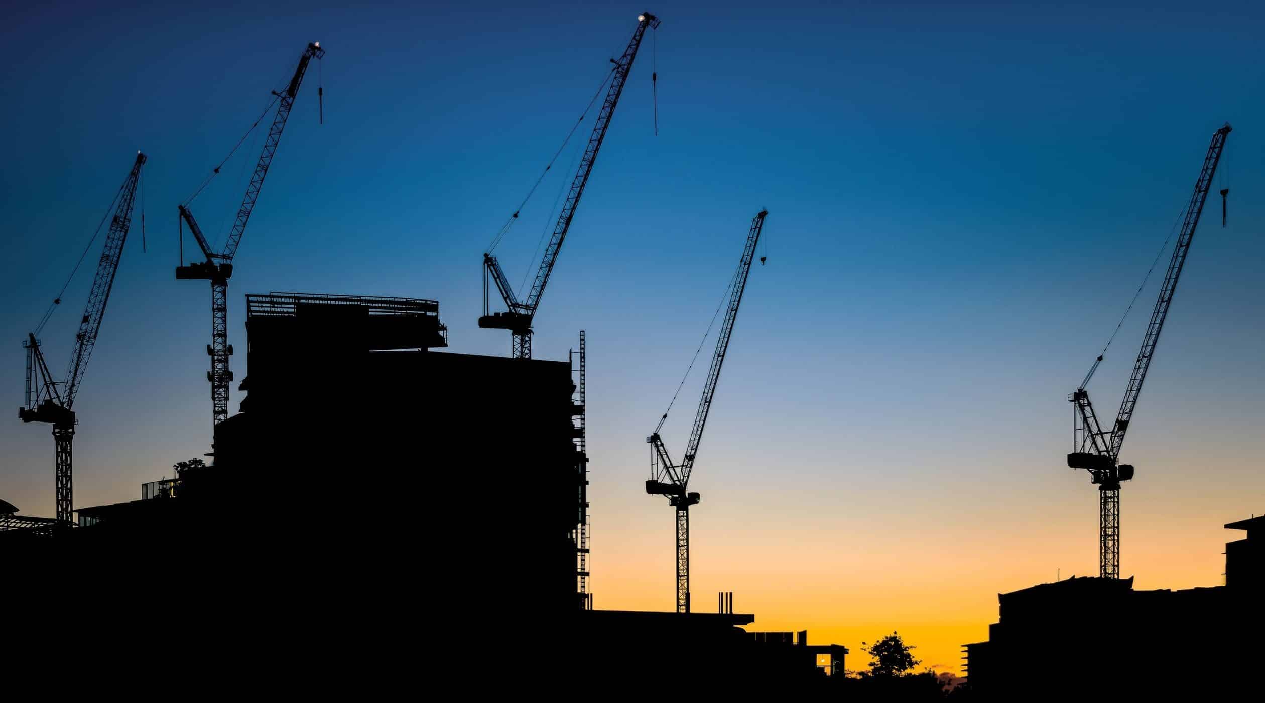 Silhouette of construction cranes at sunset.