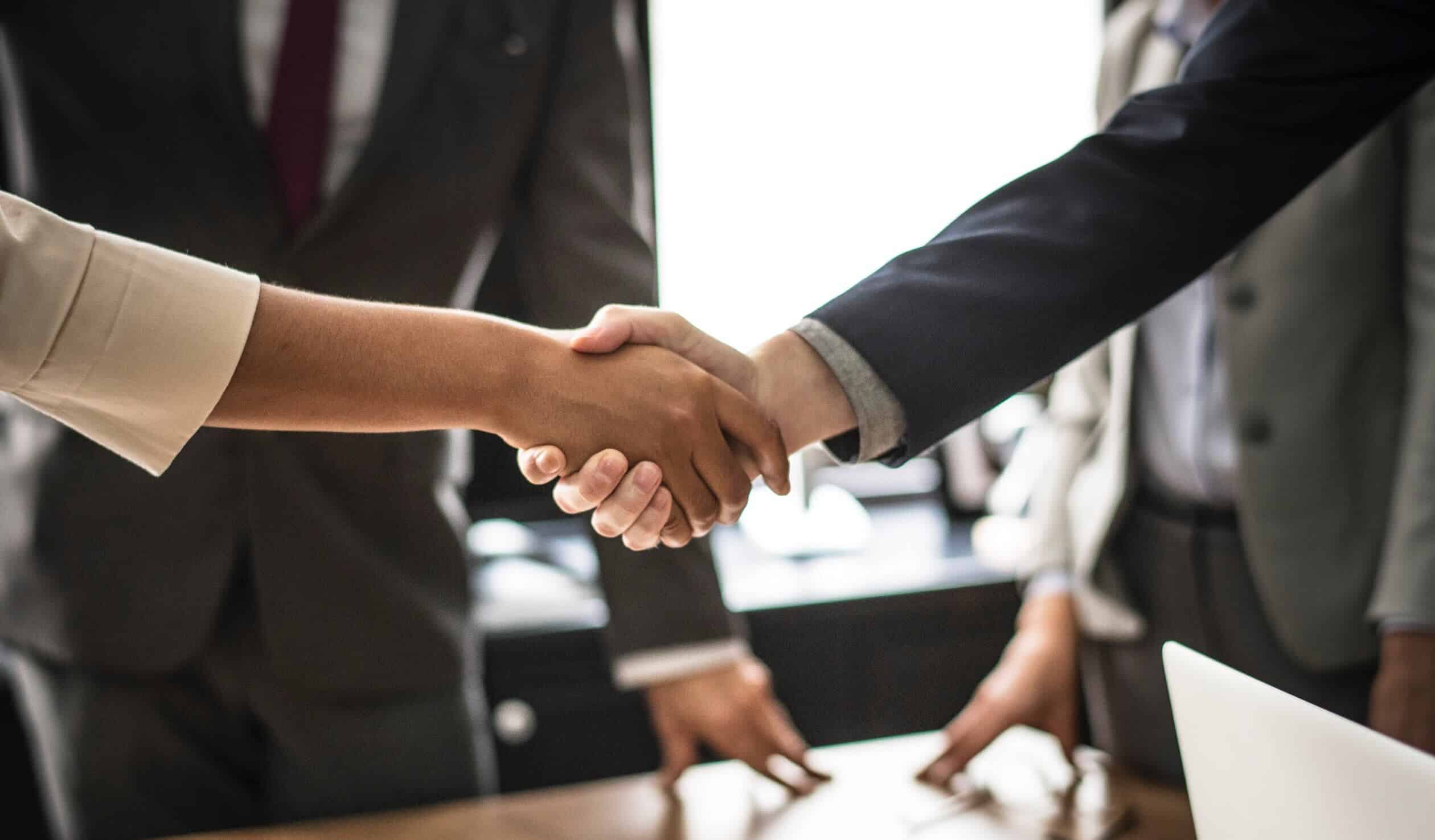 A group of business people shaking hands over a table.