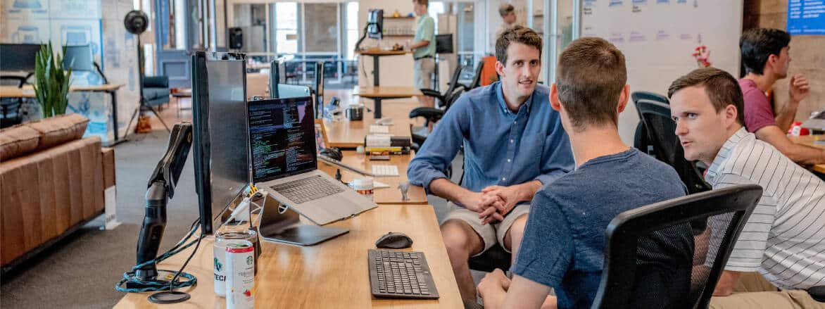 A group of people sitting at a desk in an office.