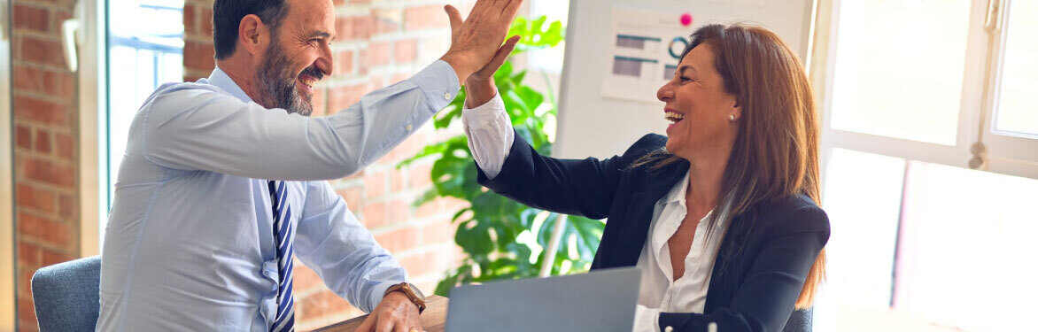 A man and woman giving each other high fives in an office.