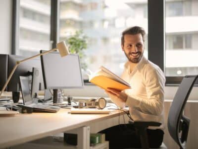 A man sitting at his desk reading a book.