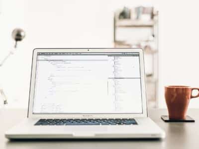 A laptop is sitting on a desk next to a coffee mug.