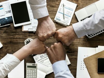 A group of business people forming a fist around a table.