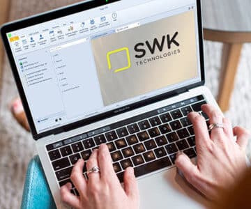 A woman typing on a laptop with the word SWK on it.