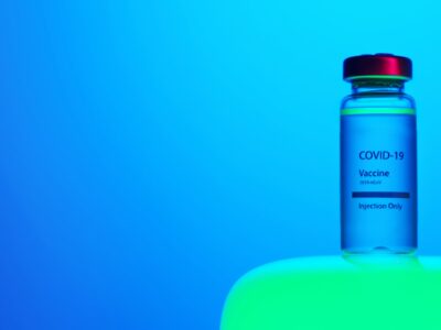 A bottle of coronavirus vaccine sitting on top of a blue background.