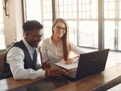 Two business people working on a laptop in an office.