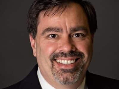 A man in a suit and tie smiles for the camera.