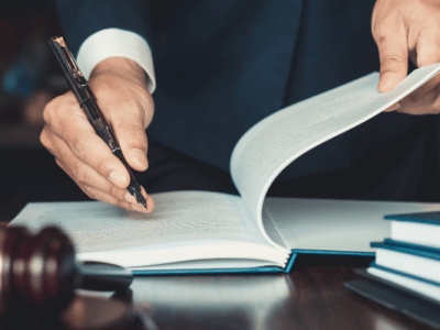 A man in a suit writing on a book.