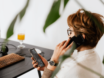 A woman talking on a cell phone while sitting at a desk.