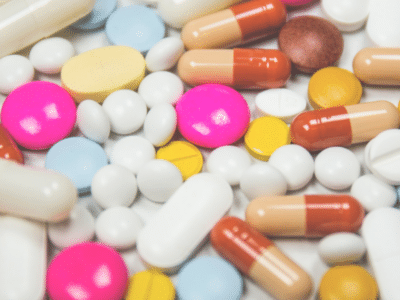 A group of colorful pills and capsules on a white surface.