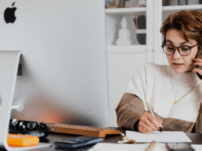 A woman is talking on the phone while sitting at her desk.