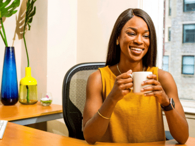 A woman in an office holding a cup of coffee.