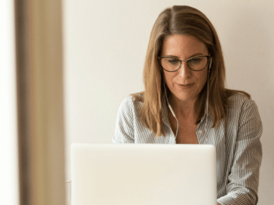 A woman wearing glasses is using a laptop.