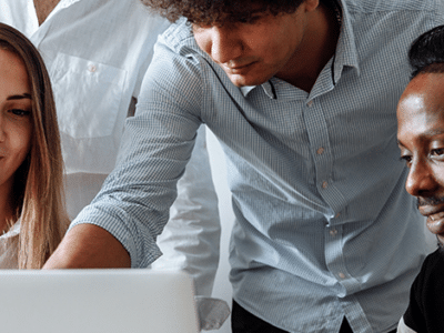 A group of people looking at a laptop.