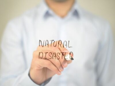 A man writing the word national disaster on a piece of paper.