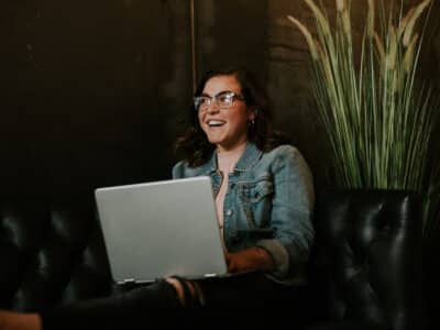 A woman sitting on a couch with a laptop.