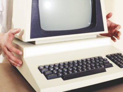 A man is holding an old computer in his hands.