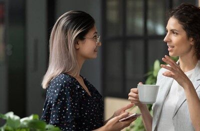 Two women talking to each other in an office.